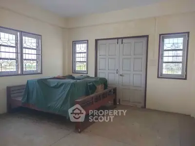 Spacious room with large windows and a covered wooden bed frame, offering potential for customization.