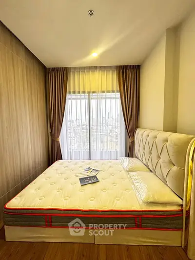 Cozy bedroom with plush bed and city view through large window, perfect for relaxation.