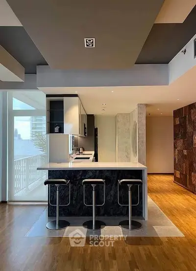 Modern kitchen with sleek design and open layout, featuring a stylish island and bar stools.