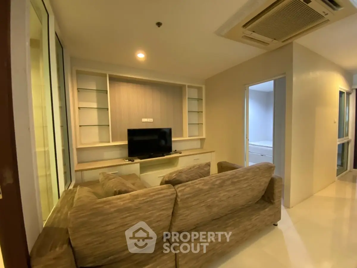 Cozy living room with modern sofa and built-in shelves, perfect for relaxation.