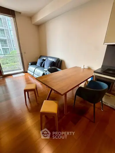 Modern living room with wooden flooring, stylish furniture, and balcony access in a contemporary apartment.