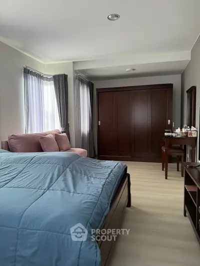 Spacious bedroom with elegant wooden wardrobe and cozy seating area