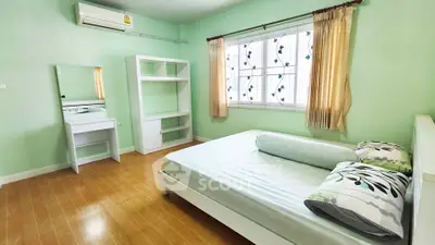 Cozy bedroom with mint green walls, wooden flooring, and elegant window drapes.