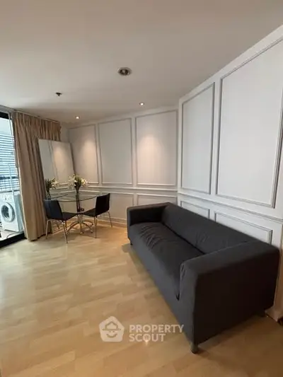 Chic modern living room with sleek black sofa and elegant dining area, perfect for urban living.