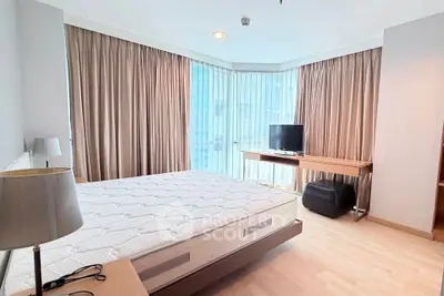 Spacious bedroom with large windows and modern furnishings in a luxury apartment.