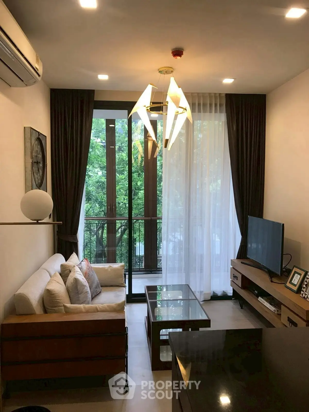 Modern living room with stylish lighting and balcony view, featuring cozy seating and entertainment area.