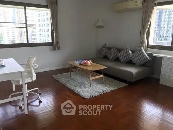 Spacious living room with modern decor and city view, featuring a cozy sofa and stylish desk.
