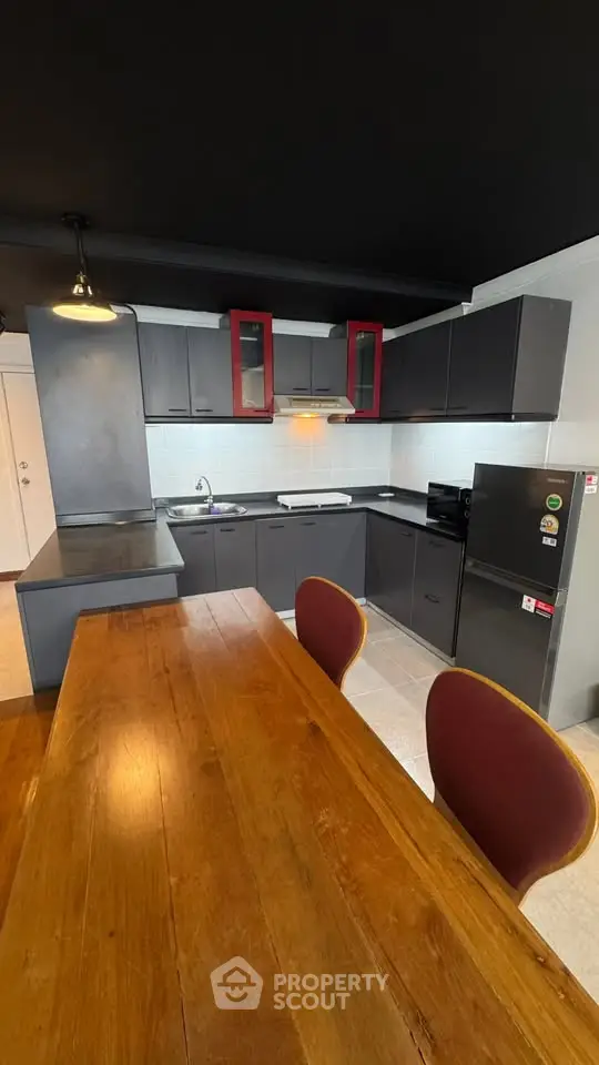 Modern kitchen with sleek black cabinets and wooden dining table