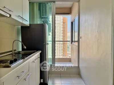 Compact kitchen with balcony view in modern high-rise apartment
