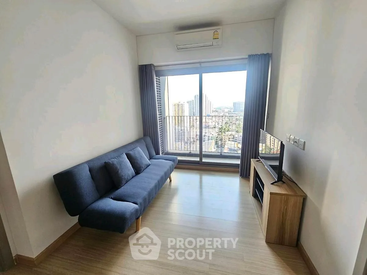Modern living room with city view, featuring sleek sofa and flat-screen TV.