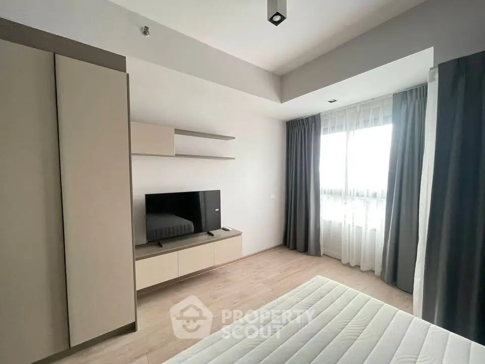 Modern bedroom with sleek design, featuring a mounted TV and ample natural light.