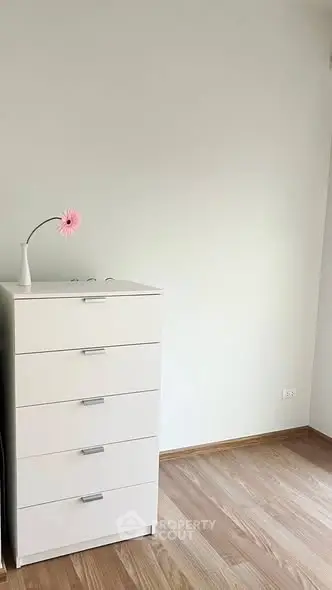 Minimalist bedroom with white dresser and wooden flooring