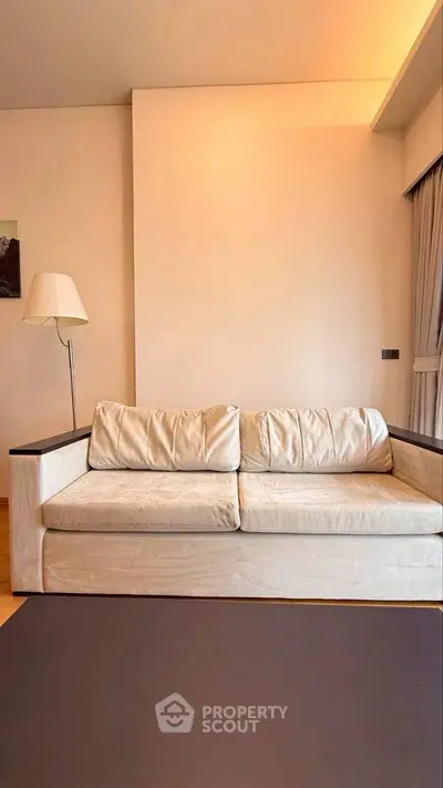 Cozy living room with plush beige sofa and modern floor lamp, perfect for relaxation.