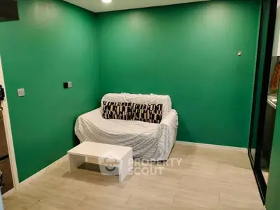 Cozy living room with green walls and a comfortable sofa, perfect for relaxation.