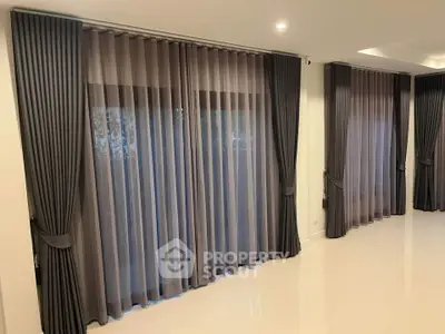 Elegant living room with floor-to-ceiling curtains and polished tile flooring