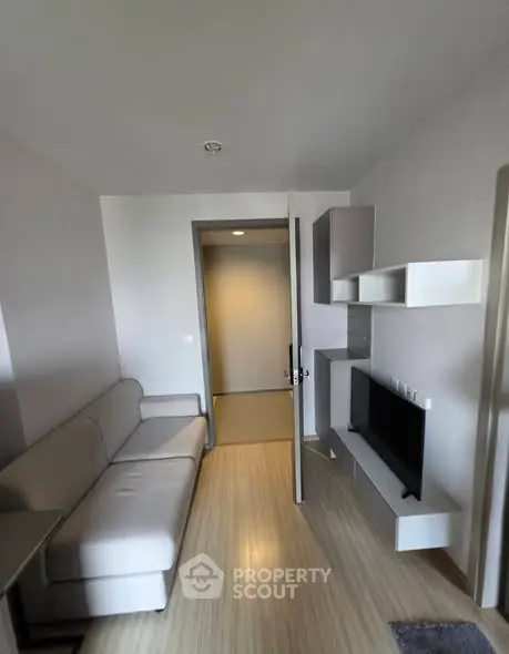 Modern living room with sleek furniture and wall-mounted TV in a cozy apartment.