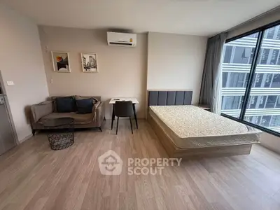 Modern studio apartment with large window and stylish furnishings