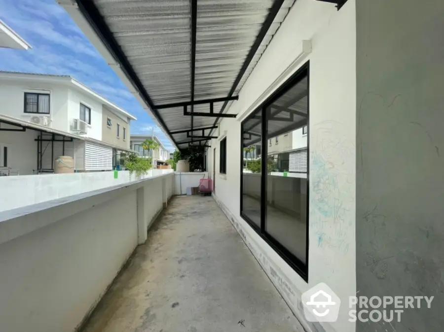 Spacious covered balcony area with potential for outdoor living space, surrounded by residential structures, offering a blend of indoor-outdoor living.