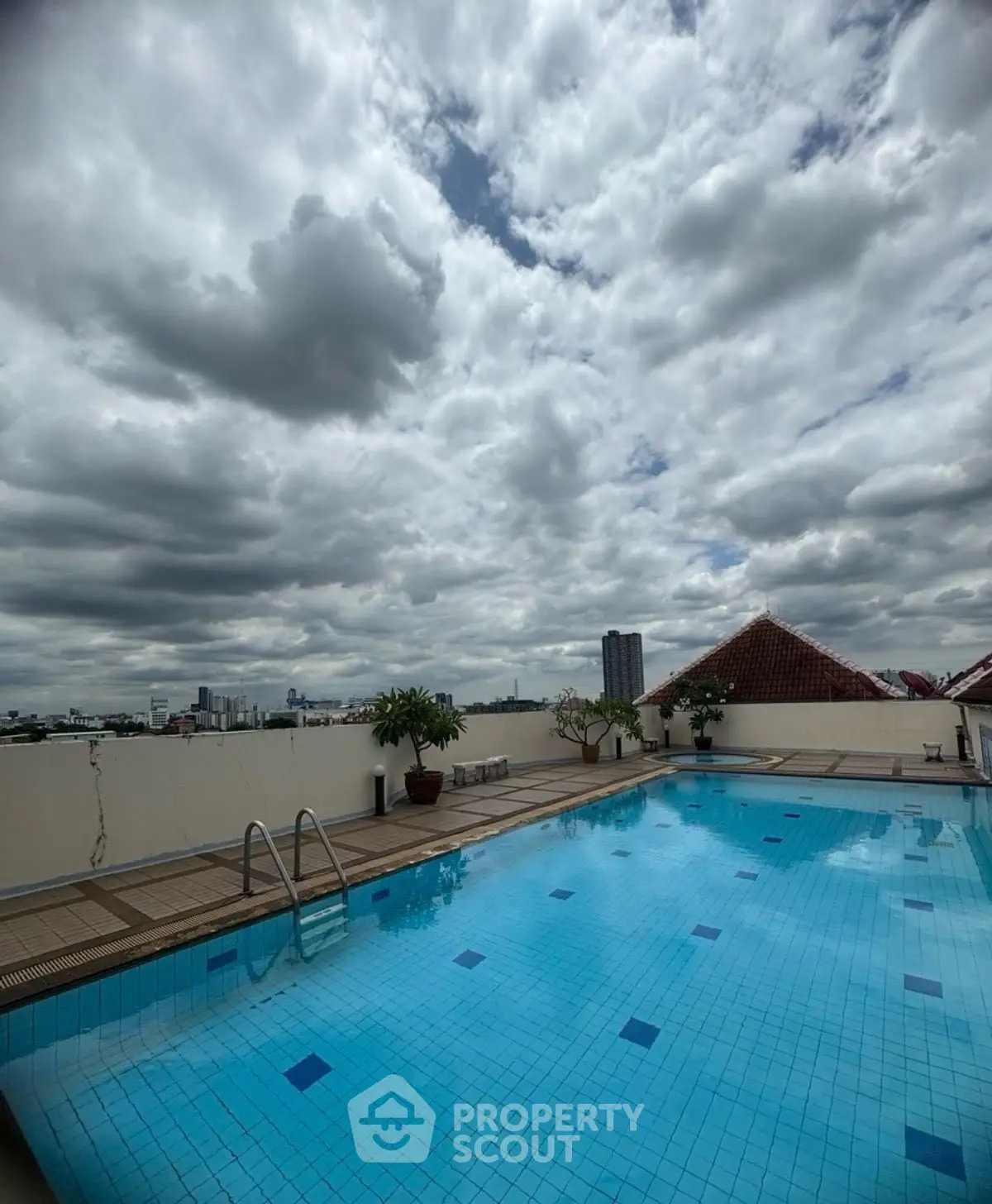 Stunning rooftop pool with panoramic city views under a dramatic cloudy sky.