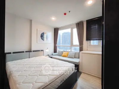 Modern bedroom with large window and city view, featuring cozy decor and ample natural light.