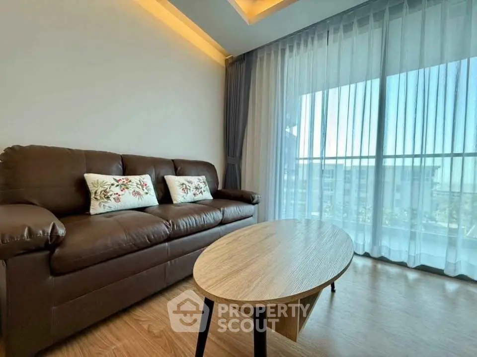 Modern living room with leather sofa and large window offering a stunning view.