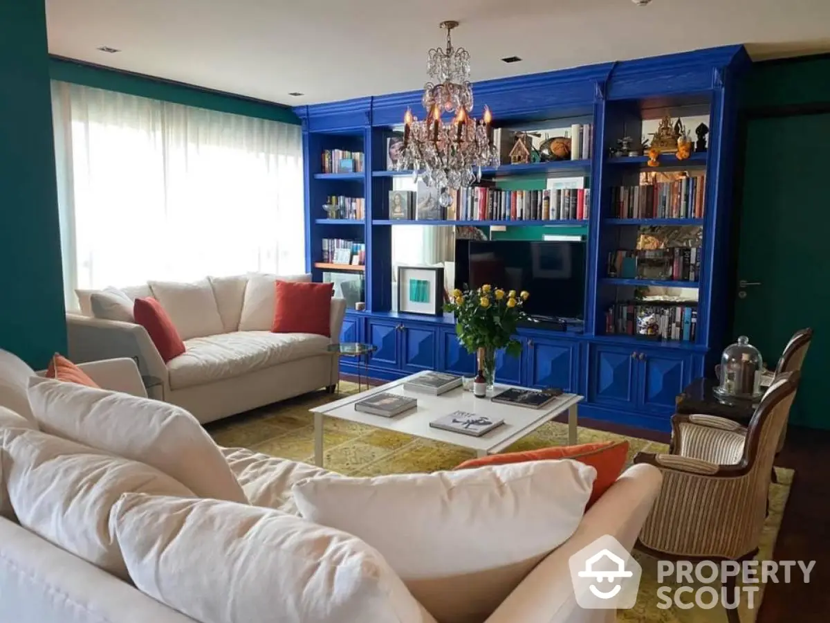 Elegant living room with blue bookshelf, chandelier, and cozy seating area