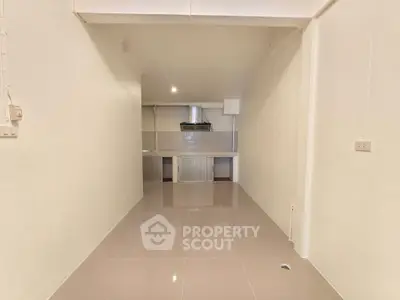 Minimalist interior space with glossy tiled flooring and open kitchen layout.