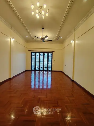 Spacious living room with elegant chandelier and polished wooden flooring