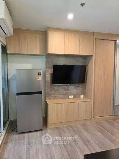 Modern living room with sleek TV setup and stainless steel fridge
