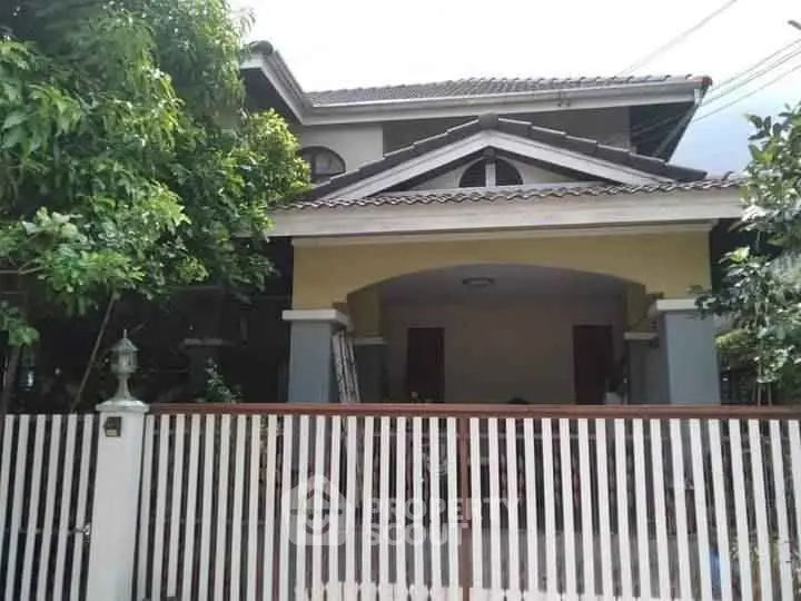 Charming two-story house with gated entrance and lush greenery, perfect for family living.