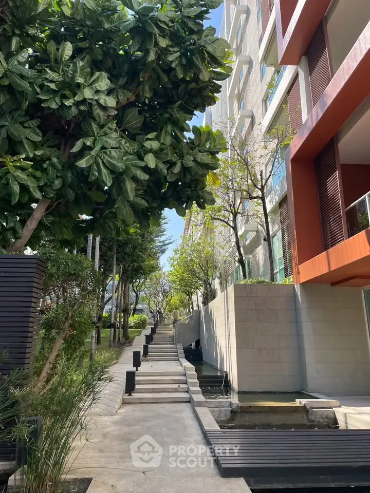Modern apartment building with lush garden pathway and contemporary design.