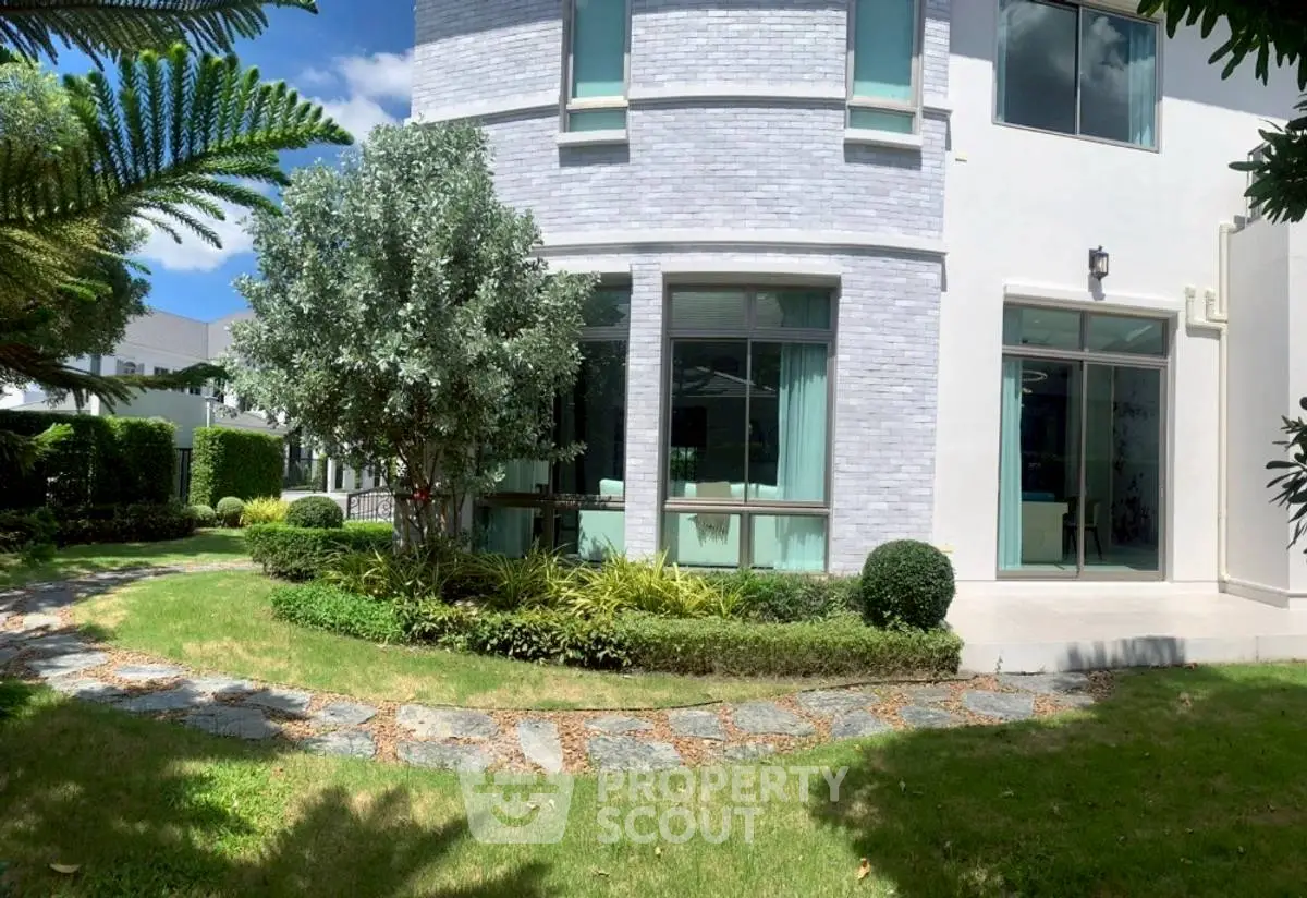 Charming modern house exterior with lush garden and stone pathway, perfect for serene living.