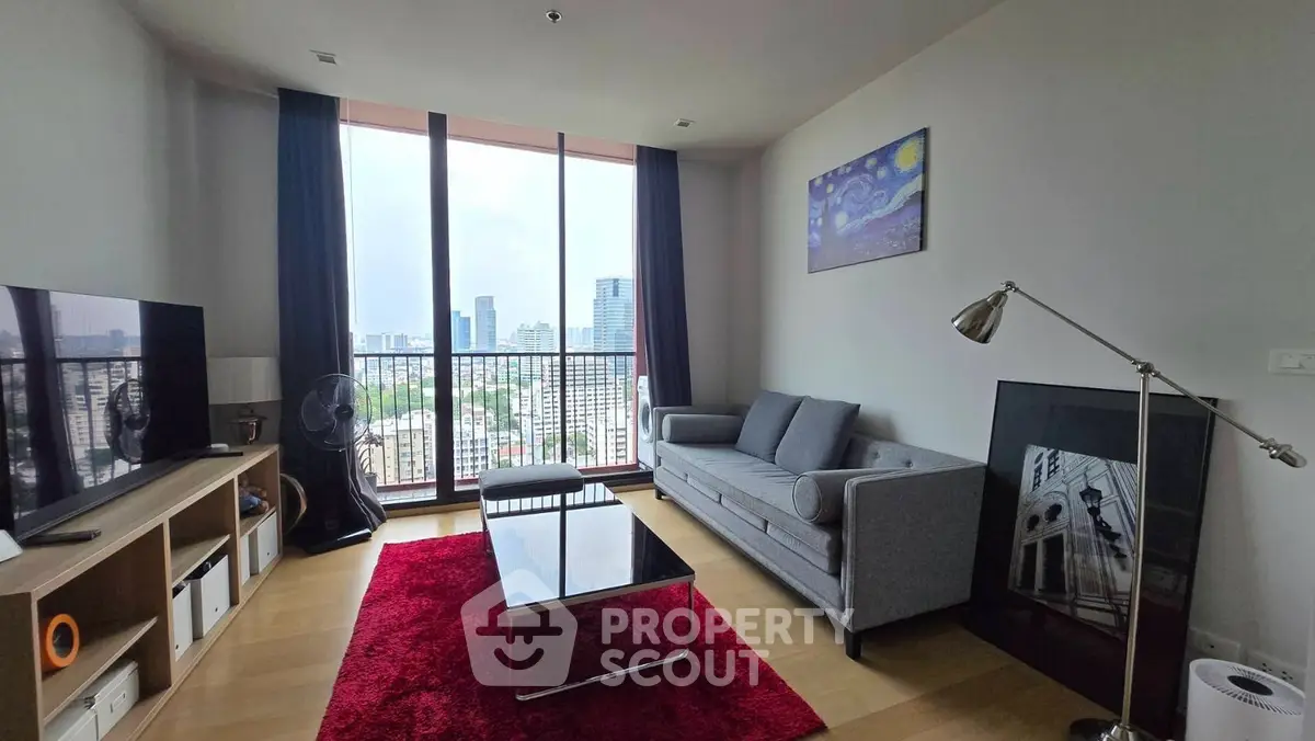 Modern living room with city view, stylish furniture, and vibrant red rug.