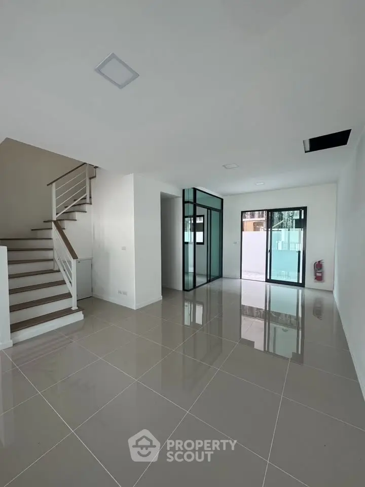 Spacious modern interior with sleek staircase and glass doors, perfect for contemporary living.