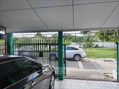 Spacious residential parking area with modern gate and lush green surroundings.