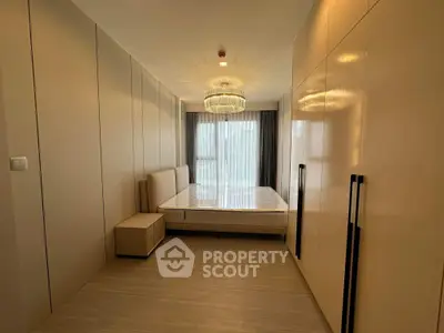 Luxurious bedroom with elegant chandelier and modern design in high-end apartment.