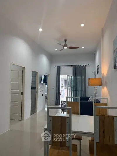 Modern living room with dining area and ceiling fan, featuring sleek design and natural light.