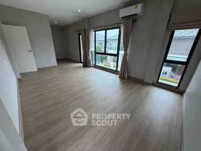 Spacious empty room with large windows and wooden flooring, perfect for customization.