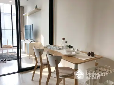 Modern dining area with natural light and stylish decor in open-plan apartment.