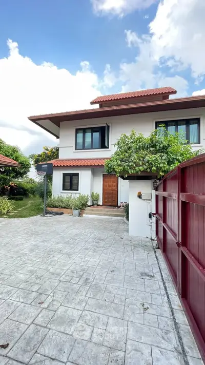 Charming two-story house with red-tiled roof and lush greenery, perfect for family living.