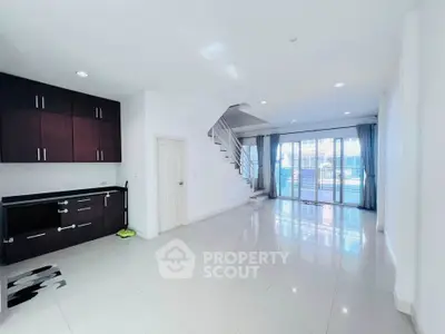 Spacious modern living room with sleek staircase and large windows for natural light.