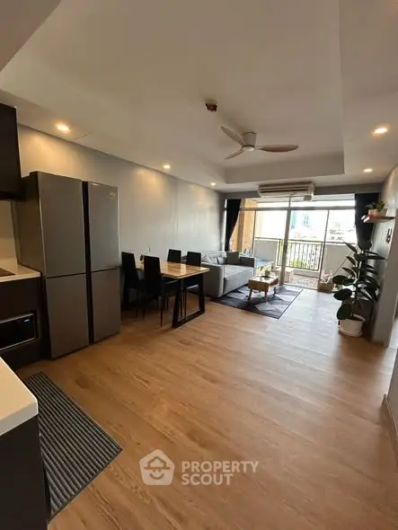 Spacious open-plan living room with modern kitchen and balcony access.