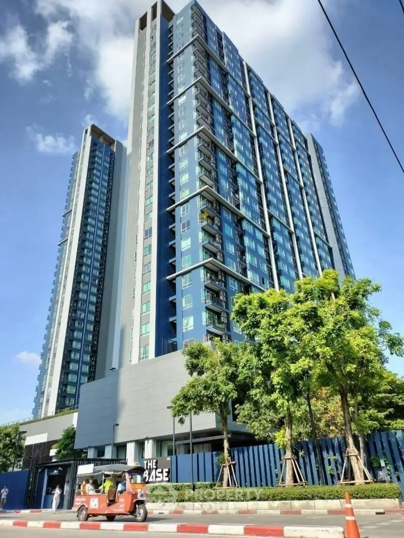 Modern high-rise building with sleek design and glass facade under clear blue sky.
