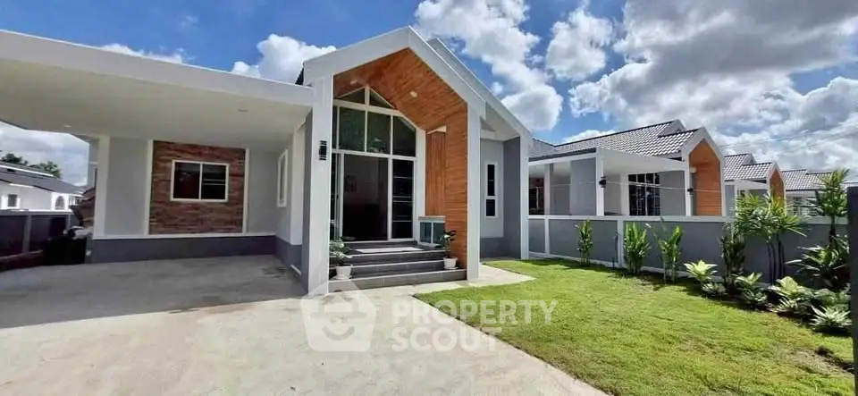 Modern single-story house with large windows and manicured lawn under a blue sky.