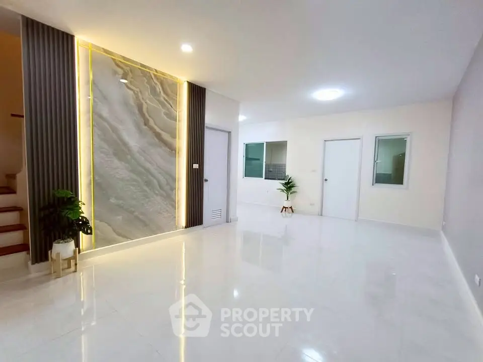Spacious modern living room with elegant lighting and marble accent wall