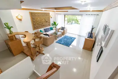 Spacious living room with elegant decor and natural light, featuring a cozy seating area and stylish wooden accents.