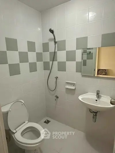 Modern bathroom with sleek white tiles and minimalist fixtures, featuring a shower and compact sink.