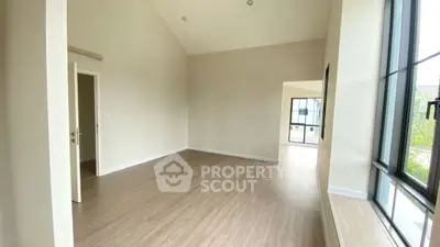 Spacious empty room with large windows and wooden flooring, ideal for customization.