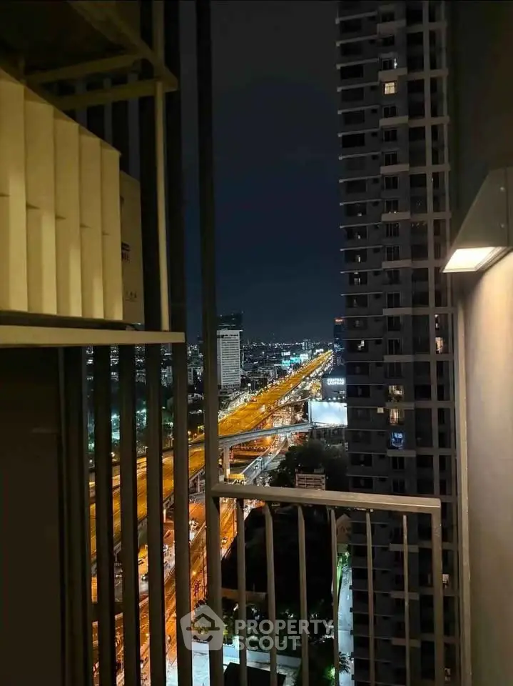 Stunning high-rise balcony view of city skyline at night with illuminated highway.