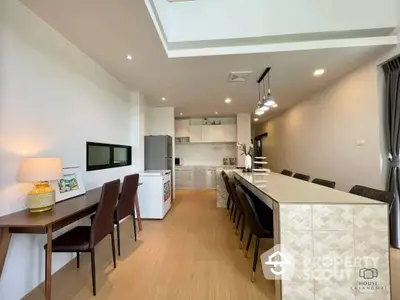 Spacious open-plan living area with modern kitchen, sleek cabinetry, and stainless steel appliances, complemented by a cozy dining space and elegant lighting.